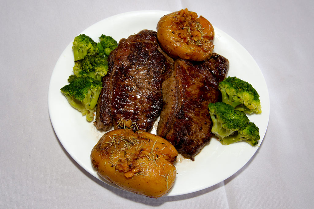 A imagem apresenta um prato branco com bife de chorizo, brócolis e batata.